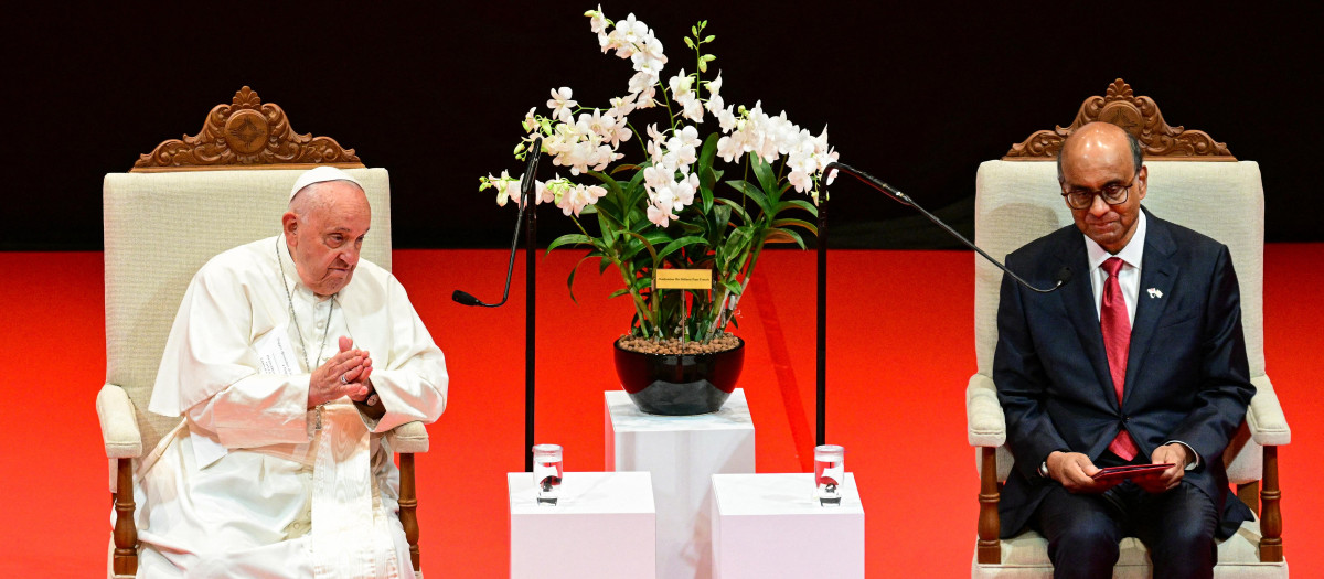 Pope Francis listens as Singapore President Tharman Shanmugaratnam (R) speaks at the Theatre of the University Cultural Centre in Singapore on September 12, 2024, as the orchid "Dendrobium His Holiness Pope Francis" named after him is seen between the two. Pope Francis is in Singapore, the last stop of a four-nation Asia-Pacific trip aimed at boosting the Catholic Church's standing in the world's most populous region. (Photo by Tiziana FABI / AFP)