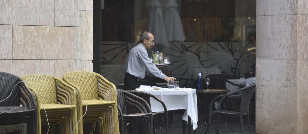 Un camarero recoge una mesa en una terraza en Huesca.