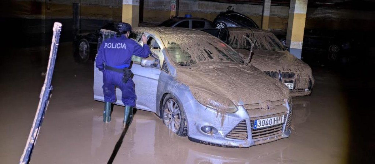 Una agente de Policía comprobando el interior de un vehículo situado en un garaje