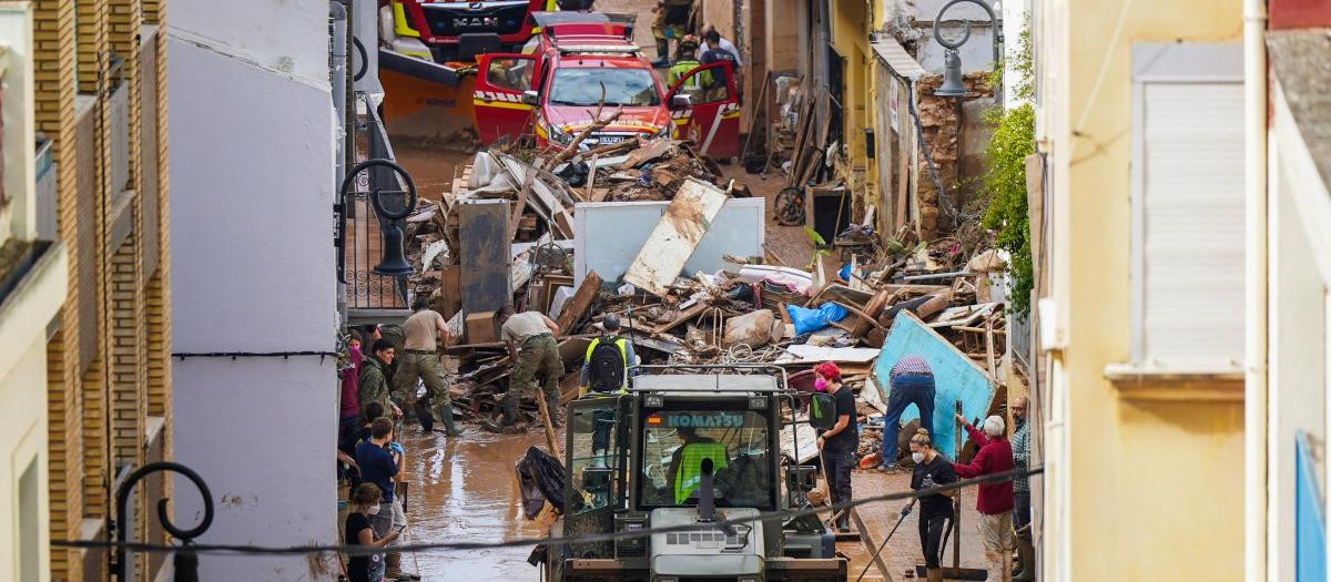 La gente trabaja para limpiar el barro y los escombros de una calle en Aldaia, en la región de Valencia