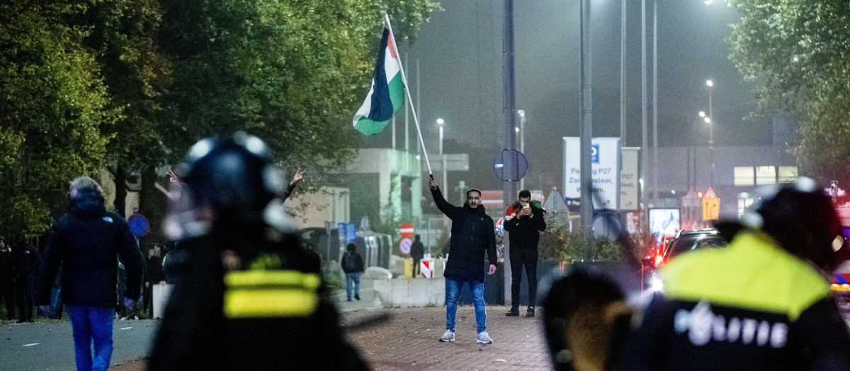 Un simpatizante ondea una bandera palestina frente a agentes de policía de la Unidad Móvil (ME) durante una manifestación pro palestina al margen del partido de fútbol de la UEFA Europa League entre el Ajax de Ámsterdam y el Maccabi Tel Aviv, en Ámsterdam