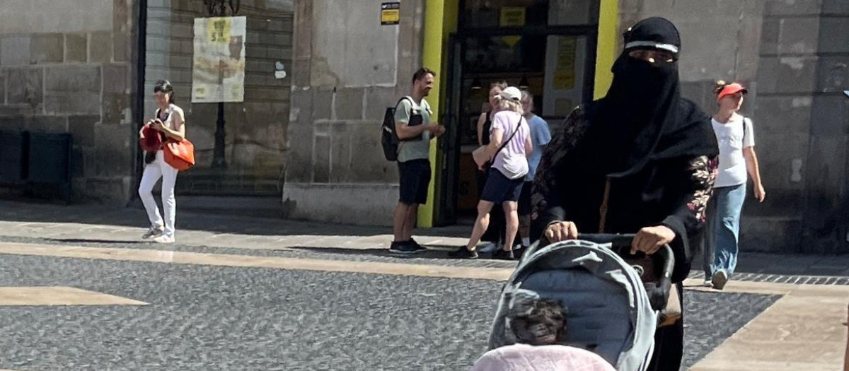 Una mujer camina por la plaza Sant Jaume de Barcelona con un velo integral