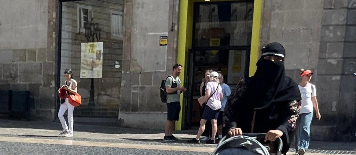 Una mujer camina por la plaza Sant Jaume de Barcelona con un velo integral