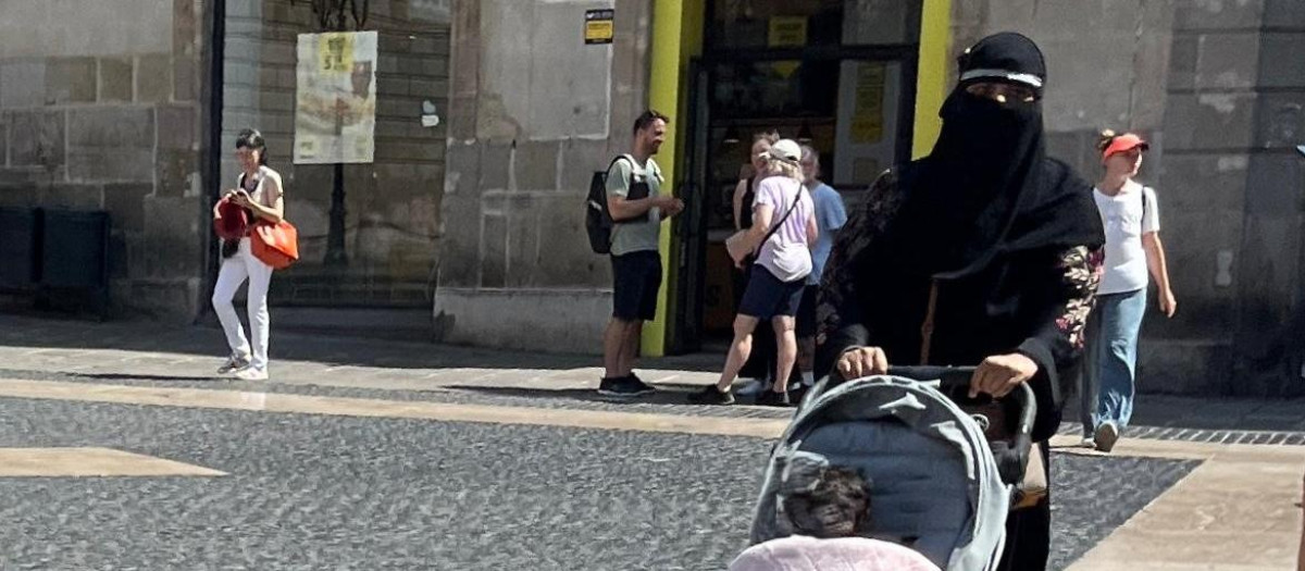 Una mujer camina por la plaza Sant Jaume de Barcelona con un velo integral