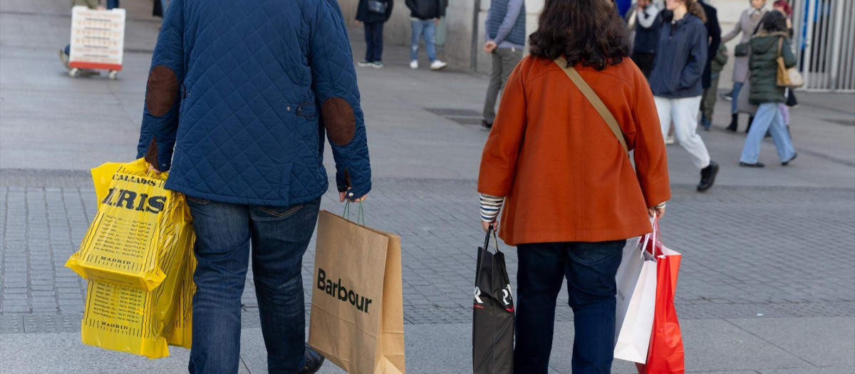 Dos personas llevan varias bolsas de compra durante Black Friday.