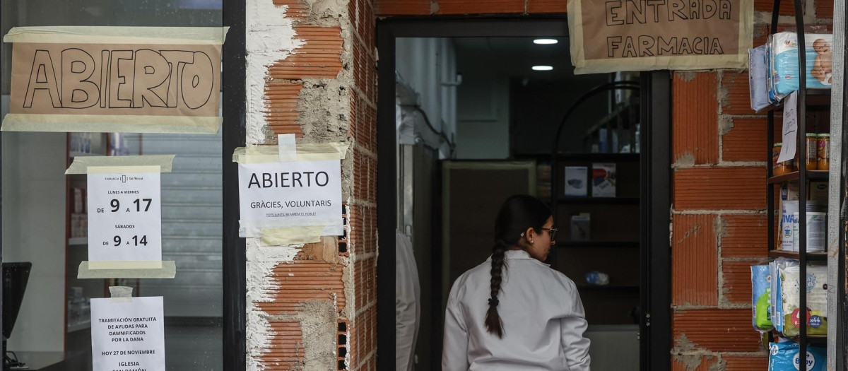 Una mujer, en la entrada de una farmacia afectada por la DANA, en Paiporta
