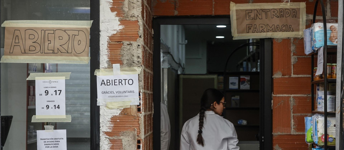 Una mujer, en la entrada de una farmacia afectada por la DANA, en Paiporta