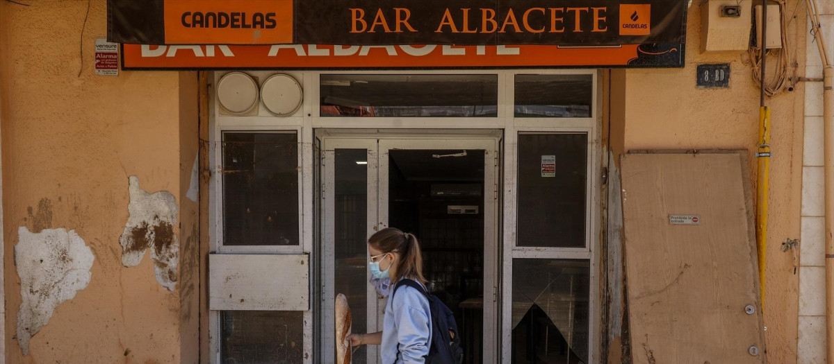 Una mujer pasa frente a la puerta de un bar de Paiporta, Valencia