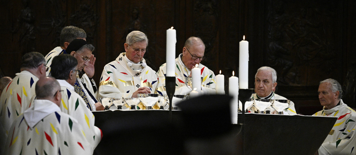 The Archbishop of Paris Laurent Ulrich (center L) leads prayers for the consecration of the new main altar, designed by French artist and designer Guillaume Bardet which replaces the old one that was destroyed in 2019, during a mass at the Notre-Dame de Paris cathedral, in Paris on December 8, 2024. Newly restored Notre Dame cathedral is set to hold its first service for the public on December 8, 2024 after a historic re-opening ceremony that saw firefighters, builders and artists celebrated for their work saving the 12th-century masterpiece. The beloved Paris monument nearly burned down in 2019, but has been renovated inside and fitted with a new roof and spire during a frenzied reconstruction effort since then. (Photo by JULIEN DE ROSA / AFP) / RESTRICTED TO EDITORIAL USE - MANDATORY MENTION OF THE ARTIST UPON PUBLICATION - TO ILLUSTRATE THE EVENT AS SPECIFIED IN THE CAPTION