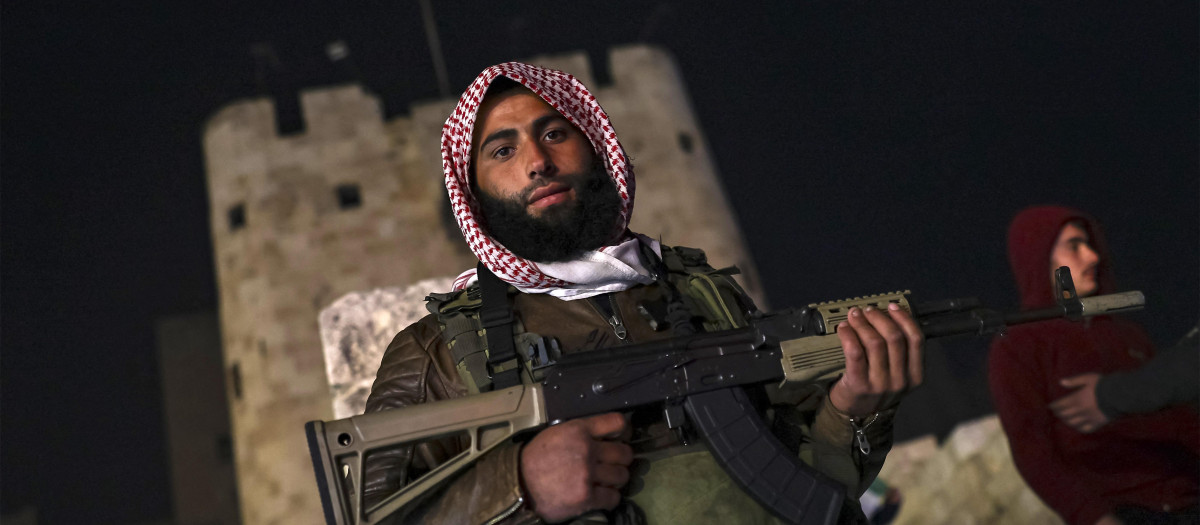 Un combatiente rebelde sirio posa para una fotografía con un fusil de asalto mientras hace guardia en la ciudadela de Alepo, Siria