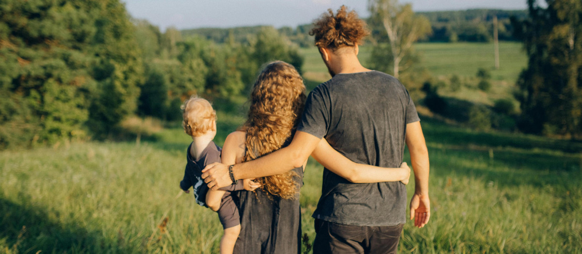 Una familia joven, frente a un paisaje arbóreo