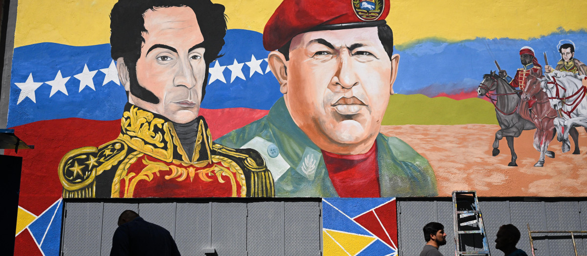 La gente pasa junto a un mural con la imagen del fallecido presidente venezolano Hugo Chávez y del libertador venezolano Simón Bolívar