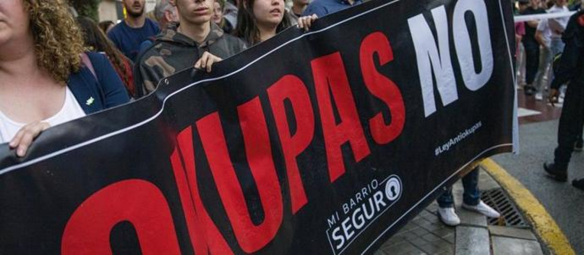 Varias personas sujetan un cartel que reza 'Okupas no' durante una protesta contra edificios ocupados