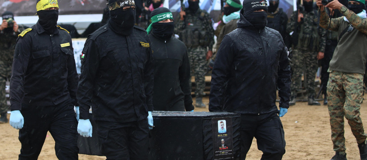 Terroristas de Hamás cargan un ataúd con el cadáver de uno de los rehenes en Gaza