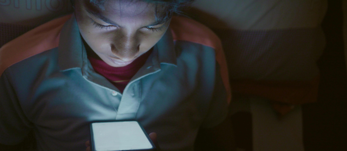 Un adolescente con el móvil por la noche
