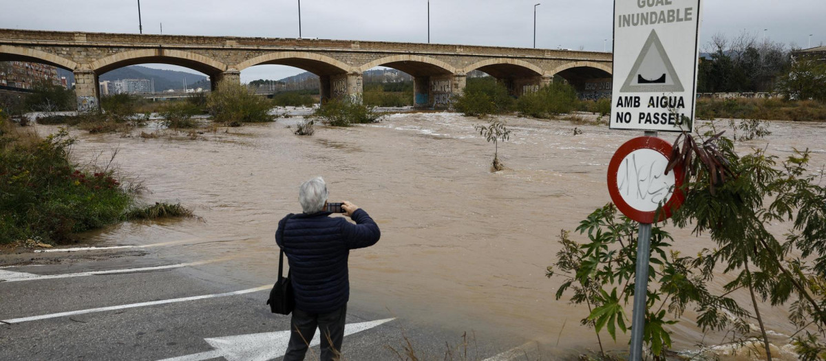 Una persona toma una imagen del caudal del río Palancia a su paso por Sagunto cuando varias carreteras de las provincias de Valencia y Castellón permanecen cortadas debido a la lluvia