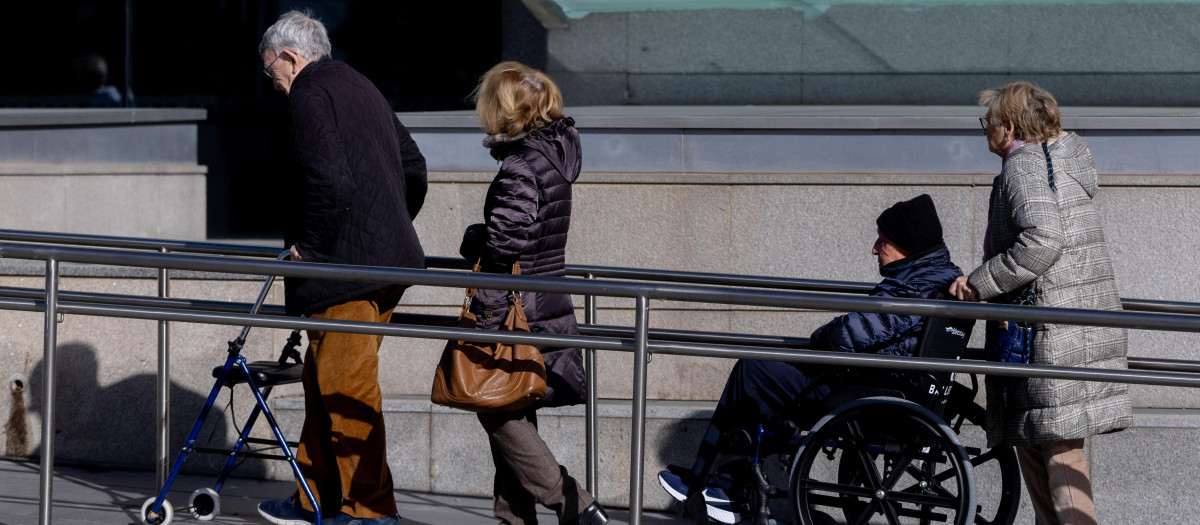 Una mujer empuja una silla de ruedas