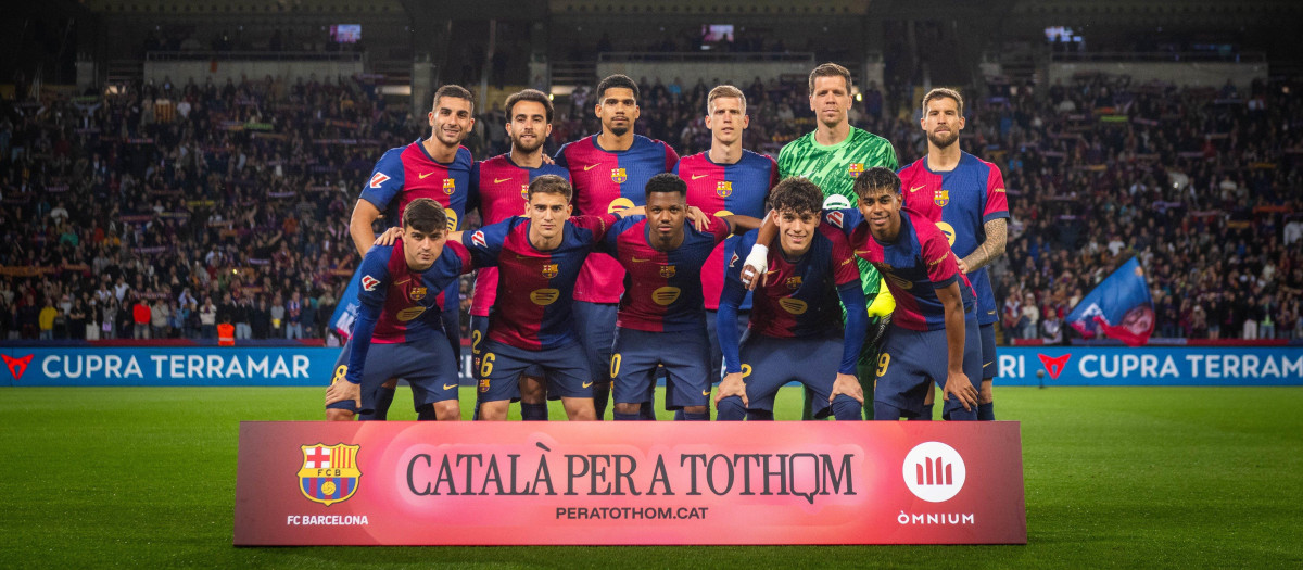 Los jugadores del Barça posan junto a la pancarta de Omnium Cultural para promocionar el uso de la lengua catalana