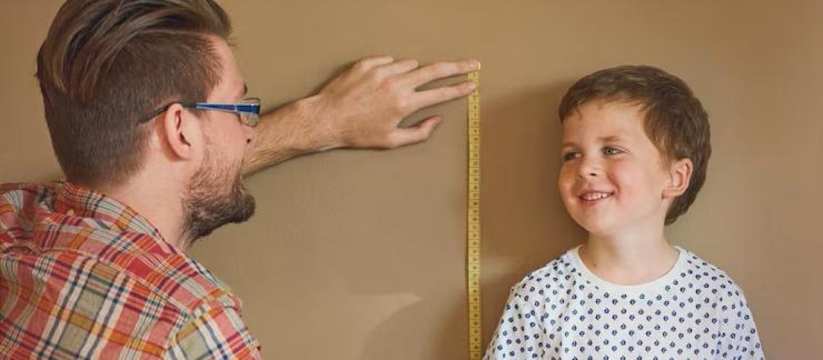 Un padre midiendo la estatura de su hijo