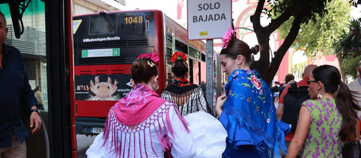 Varias mujeres de flamenca bajan de uno de los autobuses con parada en la Feria