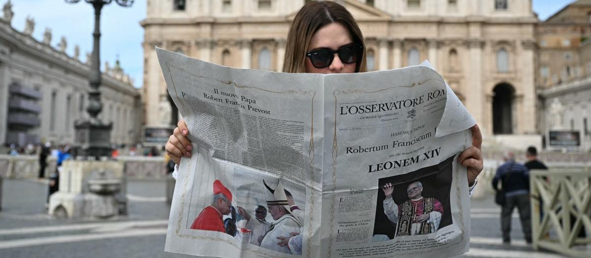 Una mujer lee L'Osservatore Romano con la noticia del nuevo Papa León XIV