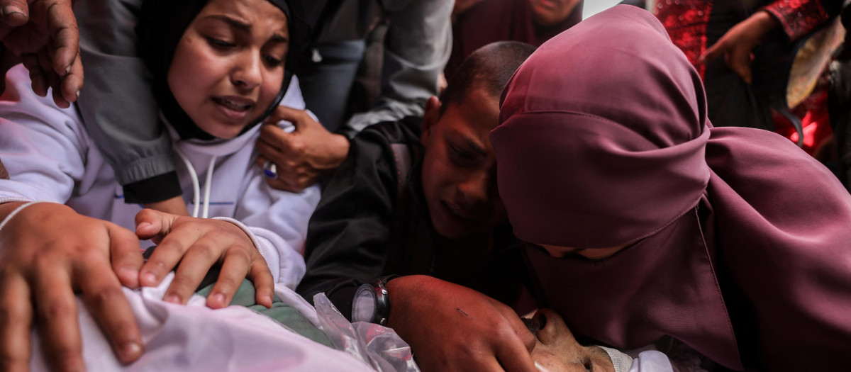 Personas lloran junto a los cuerpos envueltos en sudarios de las víctimas de los ataques israelíes en Yabalia, en el hospital indonesio de Beit Lahia, en el norte de la Franja de Gaza
