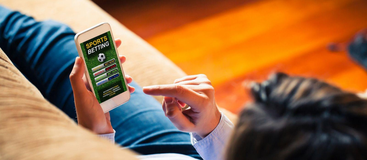Un joven apostando en una aplicación de apuestas deportivas