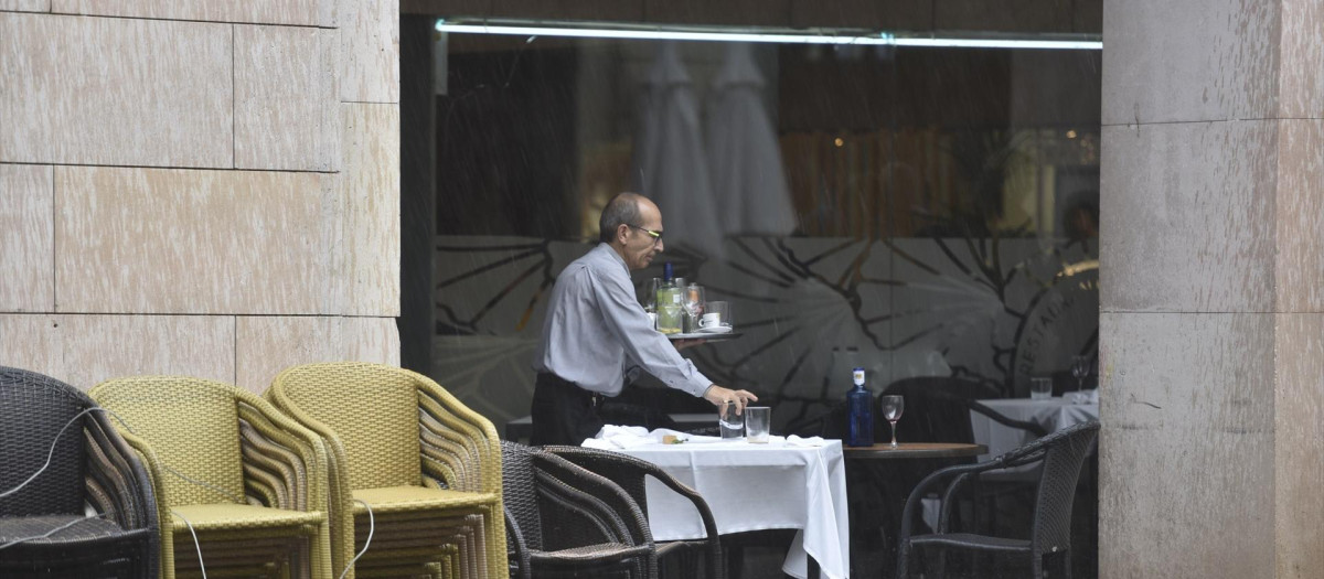 Un camarero recoge una mesa en una terraza en Huesca.