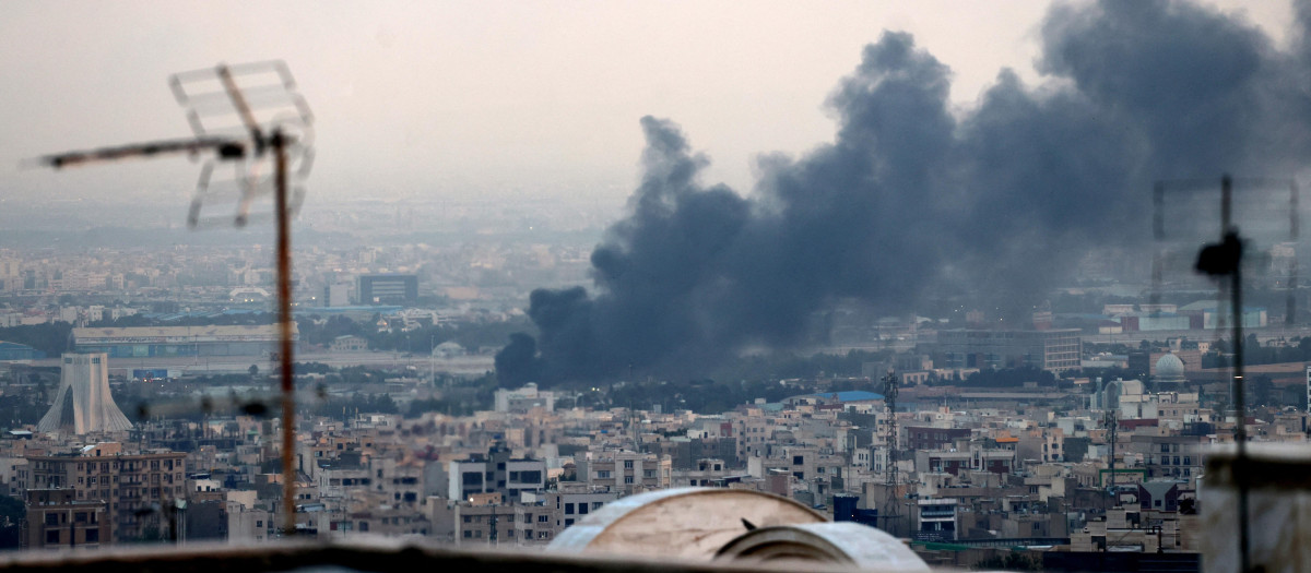 Columnas de humo se elevan tras una explosión cerca de la Torre Azadi (izq.) en Teherán el 16 de junio de 2025