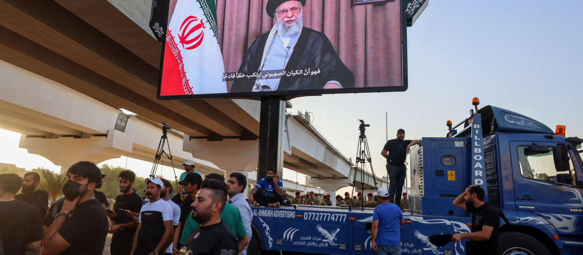 Partidarios de grupos iraquíes proiraníes exhiben una pantalla con el líder supremo de Irán, el ayatolá Alí Jamenei