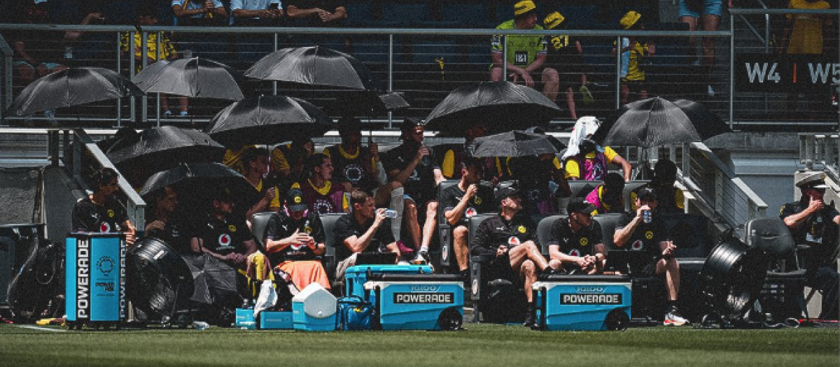 Los futbolistas del Borussia Dortmund se protegen del sol en el banquillo