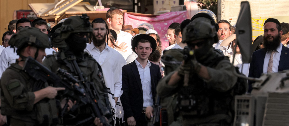 Soldados israelíes hacen guardia mientras colonos israelíes recorren el casco antiguo y el mercado de la ciudad palestina de Hebrón, en la Cisjordania