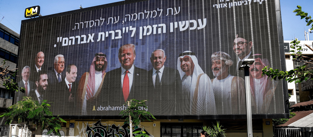 Una mujer pasa junto a una valla publicitaria colocada en Tel Aviv por la iniciativa israelí de seguridad política "Coalición para la Seguridad Regional"