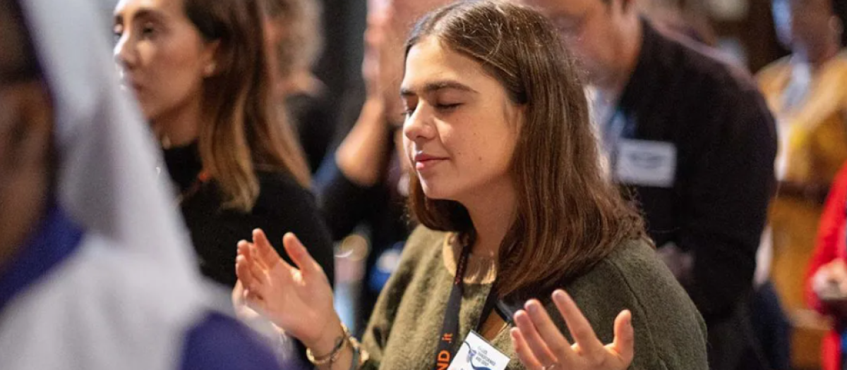 Una joven participa en una alabanza de la Renovación Carismática