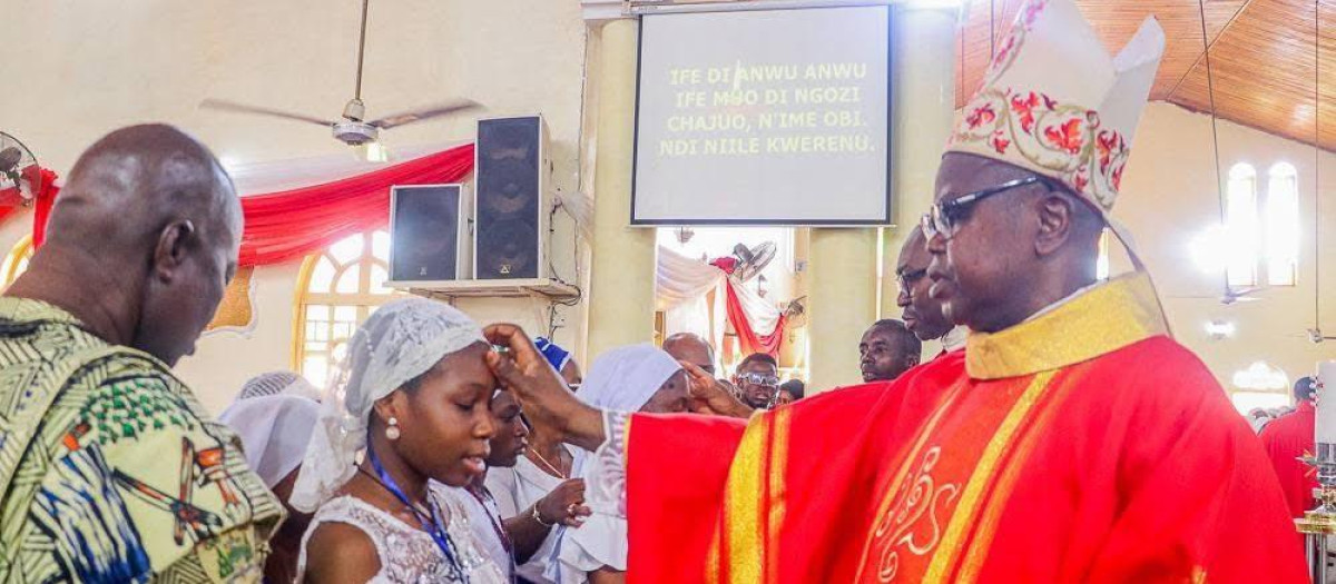 Monseñor Ernest Obodo crisma la frente de una joven nigeriana
