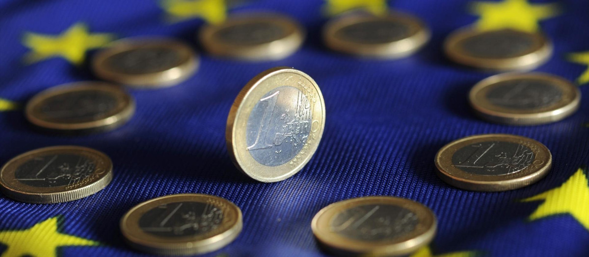 Monedas de euro sobre una bandera de la UE.