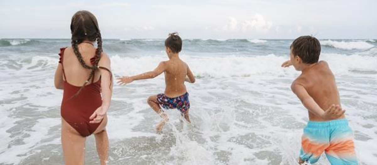 Niños entrando se adentran en un mar revuelto