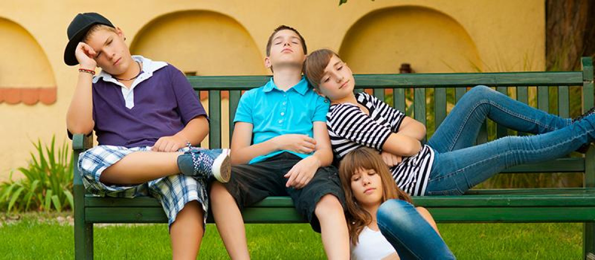 Adolescentes sentados en un banco durante las vacaciones de verano