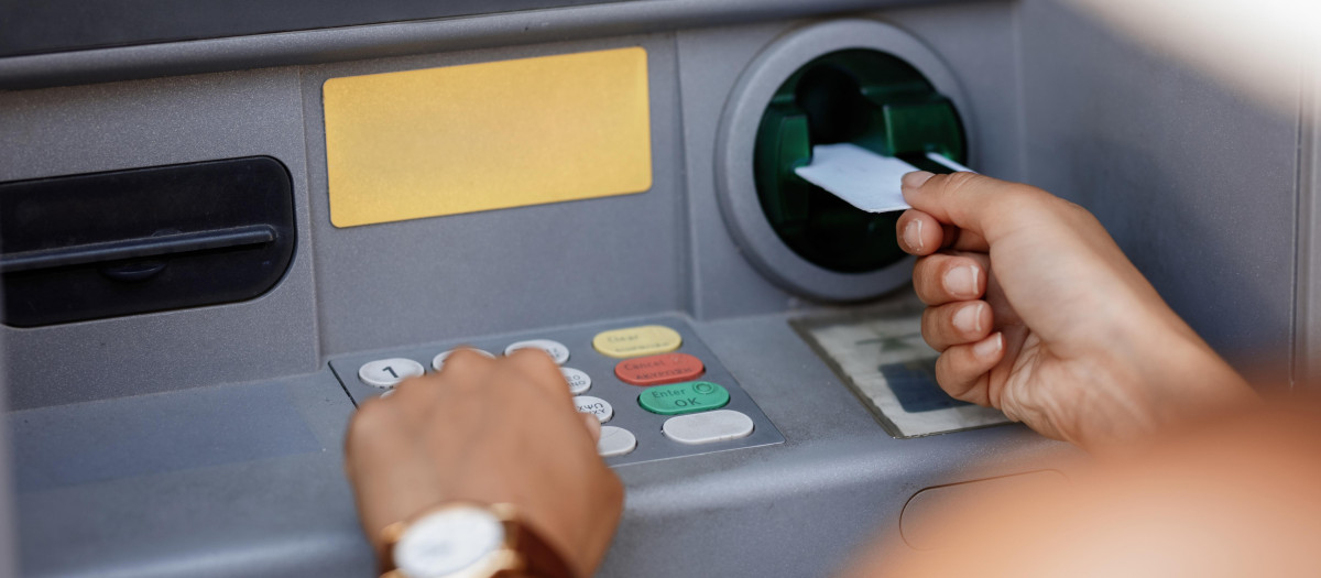 Close-up of woman typing pin code while withdrawing money from ATM.