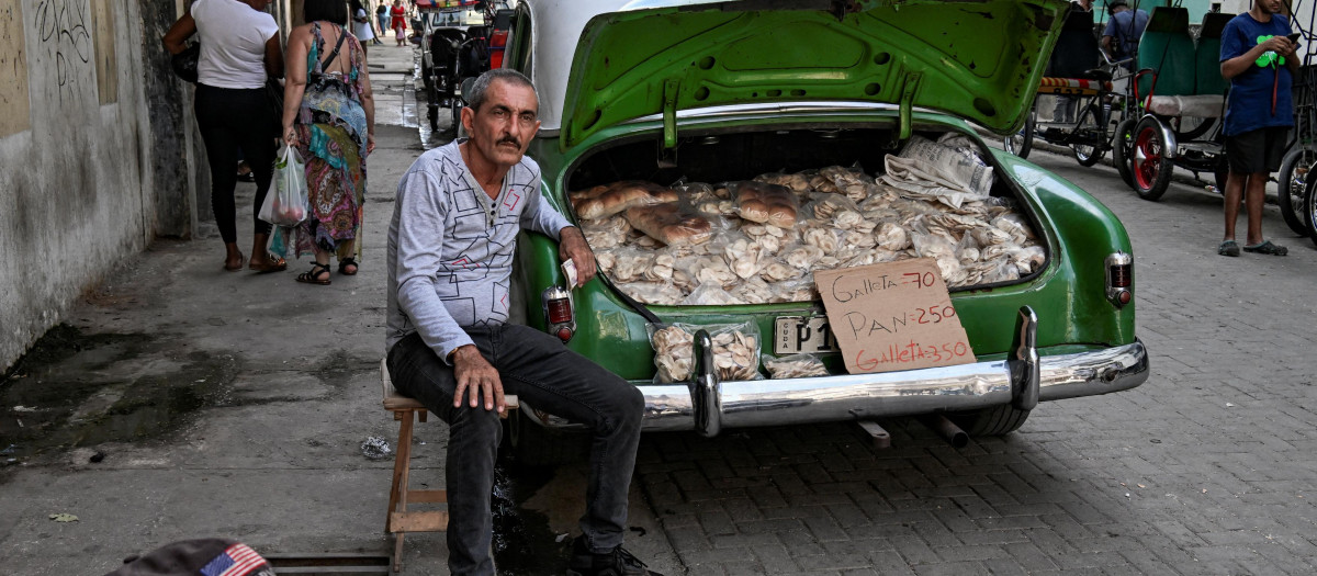 A man sells cookies displayed on an old American car in the street on the fourth anniversary of anti-government protests in Havana, on July 11, 2025. (Photo by YAMIL LAGE / AFP)