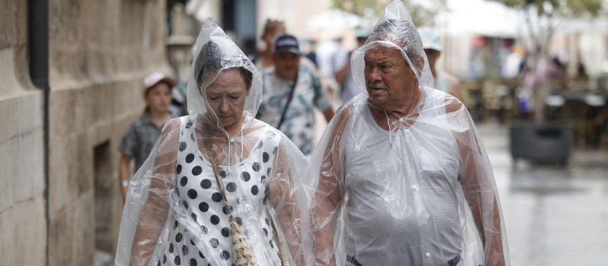 Imagen tomada este jueves de dos personas protegiéndose de la lluvia en Valencia