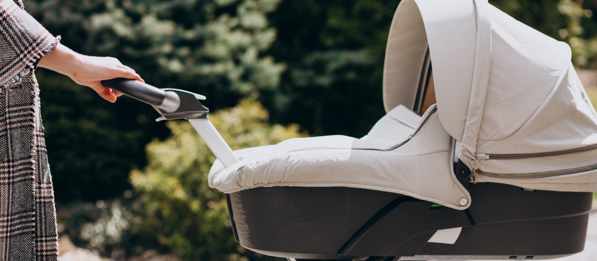 Young mother walking with baby carriage in park