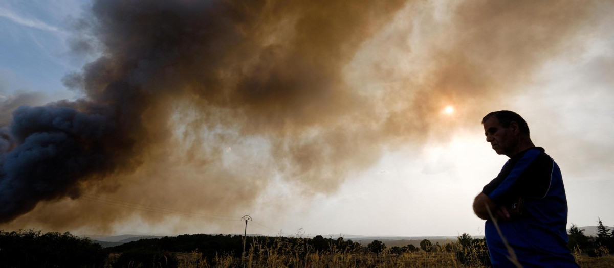 Una persona junto a una columna de humo del incendio de Las Navas del Marqués (Ávila)