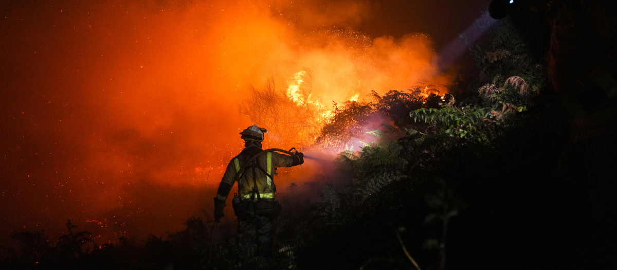 n bombero trata de extinguir el fuego, a 5 de agosto de 2025, en Ponteceso, A Coruña