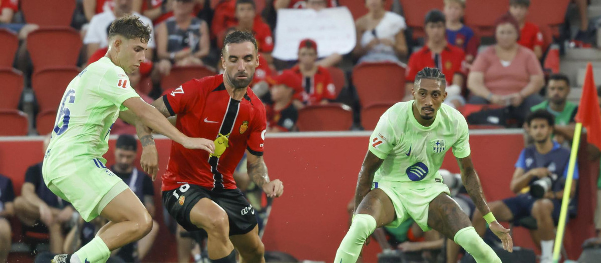 El centrocampista del Mallorca Sergi Darder (c) pelea un balón ante Fermín López (i) y Raphinha