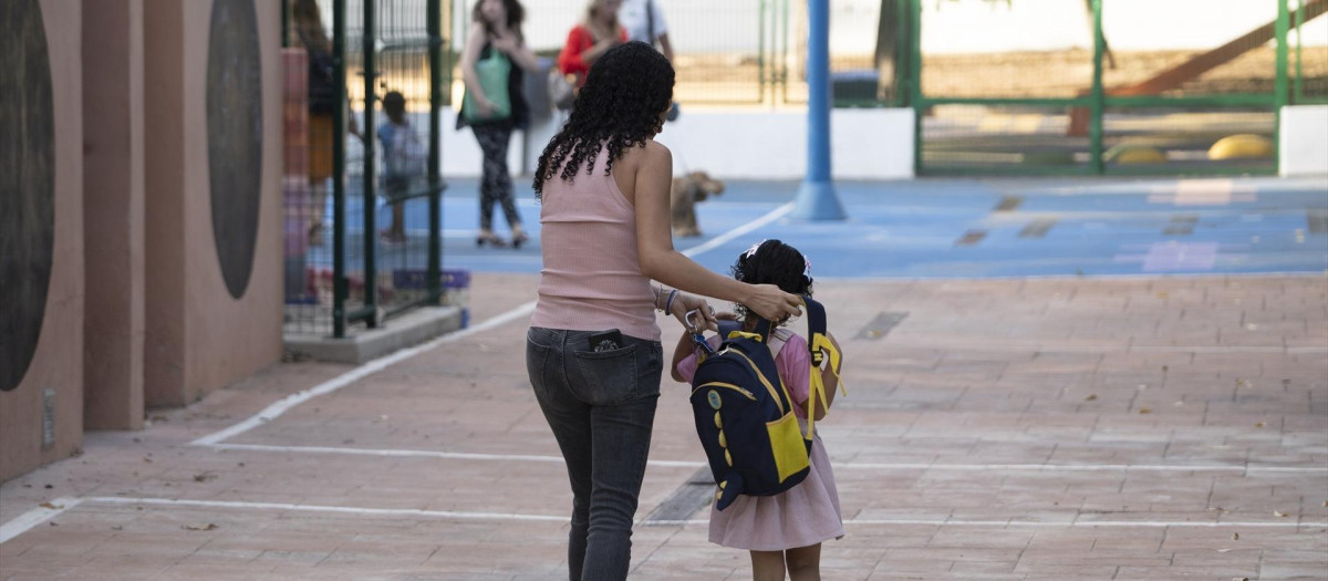 Una madre acompaña a su hija al colegio