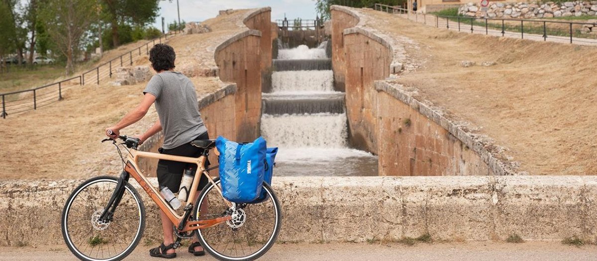 Un ciclista mira el Canal de Castilla en la exclusa de Fromista, en Palencia
