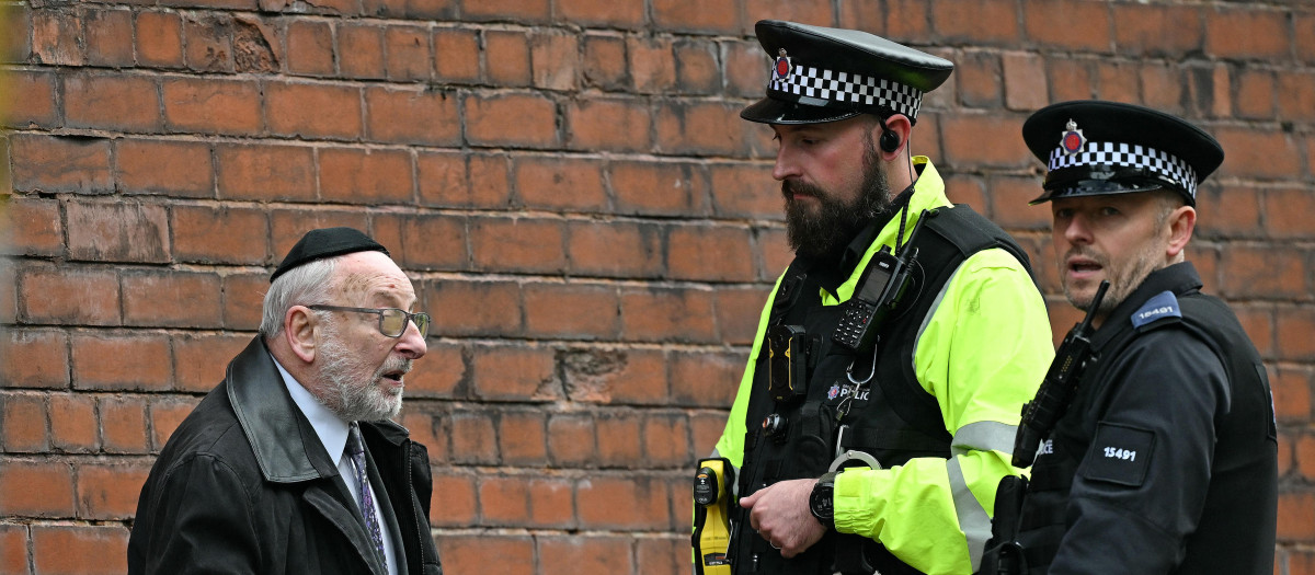 Agentes de policía conversan con un miembro de la comunidad local cerca de la sinagoga de la Congregación Hebrea de Heaton Park en Crumpsall, al norte de Mánchester