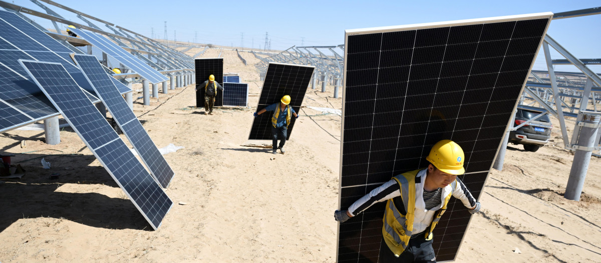 Trabajadores transportan paneles solares para su instalación en el desierto en el proyecto fotovoltaico Ningguoyun Lingwu