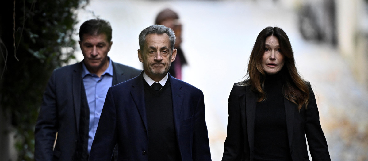 El expresidente francés Nicolas Sarkozy (izq.), acompañado de su esposa Carla Bruni-Sarkozy, sale de su residencia para presentarse en la prisión de La Santé